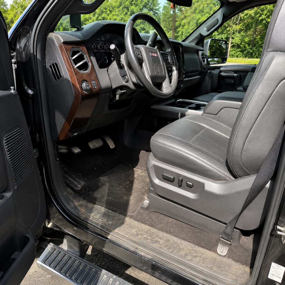 Same GMC Denali interior before detailing — dirty floor mats and dusty door sill