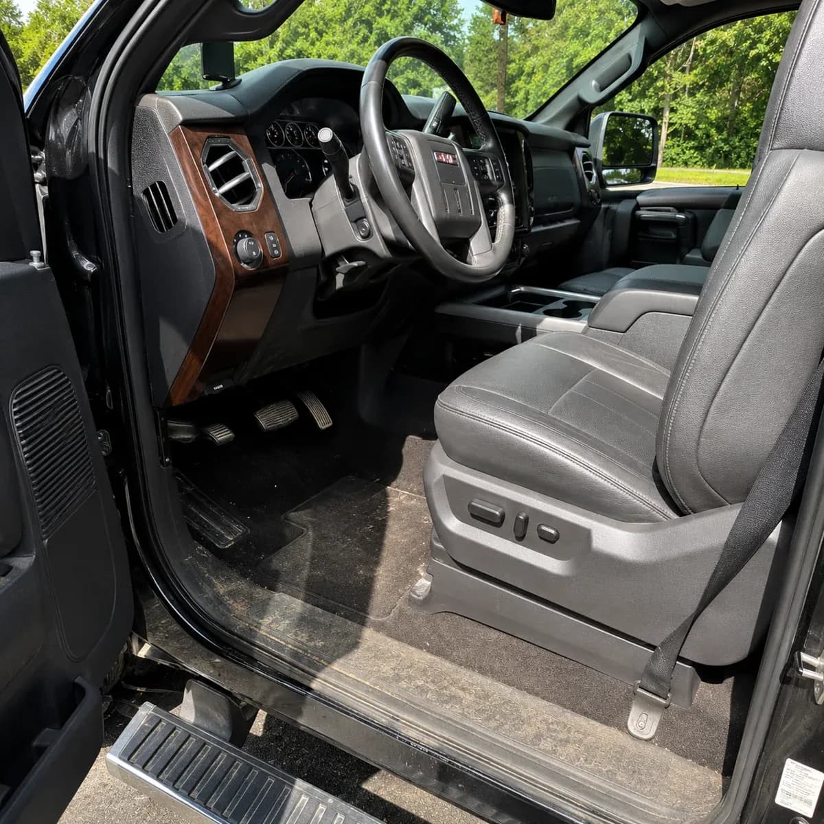 Same GMC Denali interior before detailing, dirty floor mats and dusty door sill